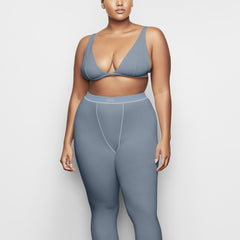 A MODEL STANDS FACING FORWARD WEARING THE COTTON RIB LEGGING