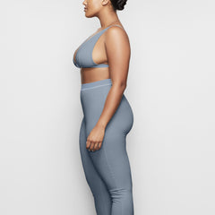 A MODEL STANDS WITH HER BACK TO THE CAMERA SHOWING THE COTTON RIB LEGGING | KYANITE