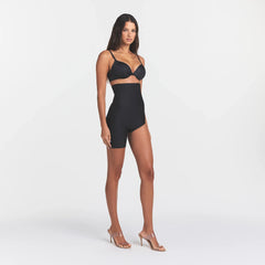 SKIMS BODY LEFT LEG SOLUTION SHORT | ONYX ON A MODEL SIDE VIEW @