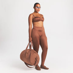 NikeSKIMS ACCESSORIES PUFFER GYM BAG | CAROB BROWN ON A MODEL FRONT VIEW @ | FOCUS: 0.0, 1.0, 0.9