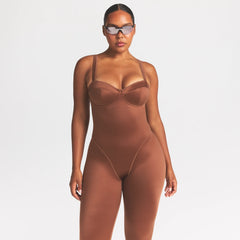 NikeSKIMS SATIN SHINE PANELED 26" ONE PIECE | CAROB BROWN ON A MODEL SIDE VIEW @ | FOCUS: 0.0, 1.0, 0.9