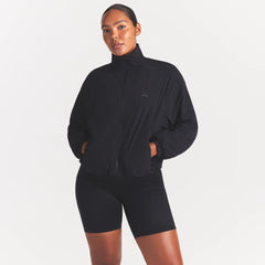 NikeSKIMS STRETCH NYLON OVERSIZED TRACK JACKET | OBSIDIAN ON A MODEL SIDE VIEW @ | FOCUS: 0.0, 1.0, 0.9