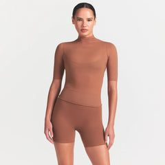 NikeSKIMS WEIGHTLESS LAYERS MOCK NECK SHORT SLEEVE T-SHIRT | CAROB BROWN ON A MODEL FRONT VIEW @ | FOCUS: 0.0, 1.0, 0.9