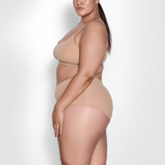 A MODEL STANDS SIDEWAYS SHOWING THE PROFILE OF THE FITS EVERYBODY BOY SHORT | OCHRE