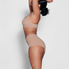 A MODEL STANDS SIDEWAYS SHOWING THE PROFILE OF THE FITS EVERYBODY BOY SHORT | SIENNA