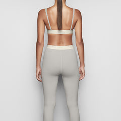 A MODEL STANDS WITH HER BACK TO THE CAMERA SHOWING THE COTTON RIB LEGGING | MINERAL