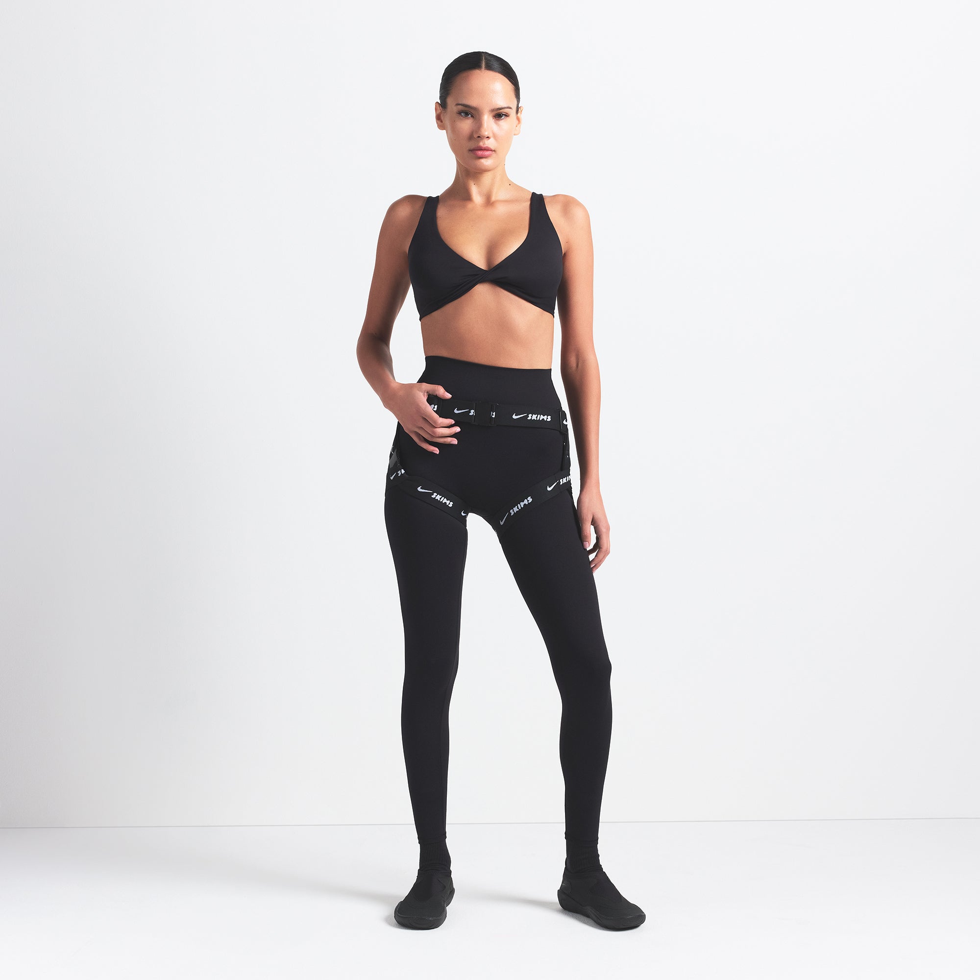 NikeSKIMS MATTE TWIST-FRONT BRA | OBSIDIAN ON A MODEL FRONT VIEW @ | FOCUS: 0.0, 1.0, 0.9