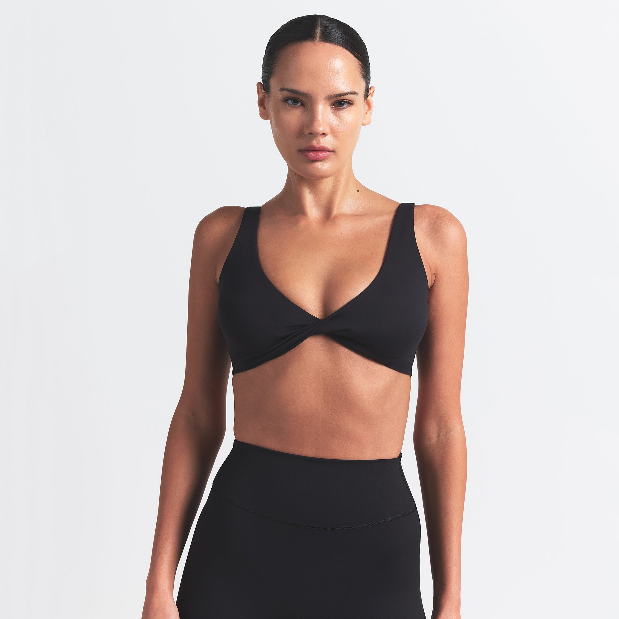 NikeSKIMS MATTE TWIST-FRONT BRA | OBSIDIAN ON A MODEL FRONT VIEW @ | FOCUS: 0.0, 1.0, 0.9