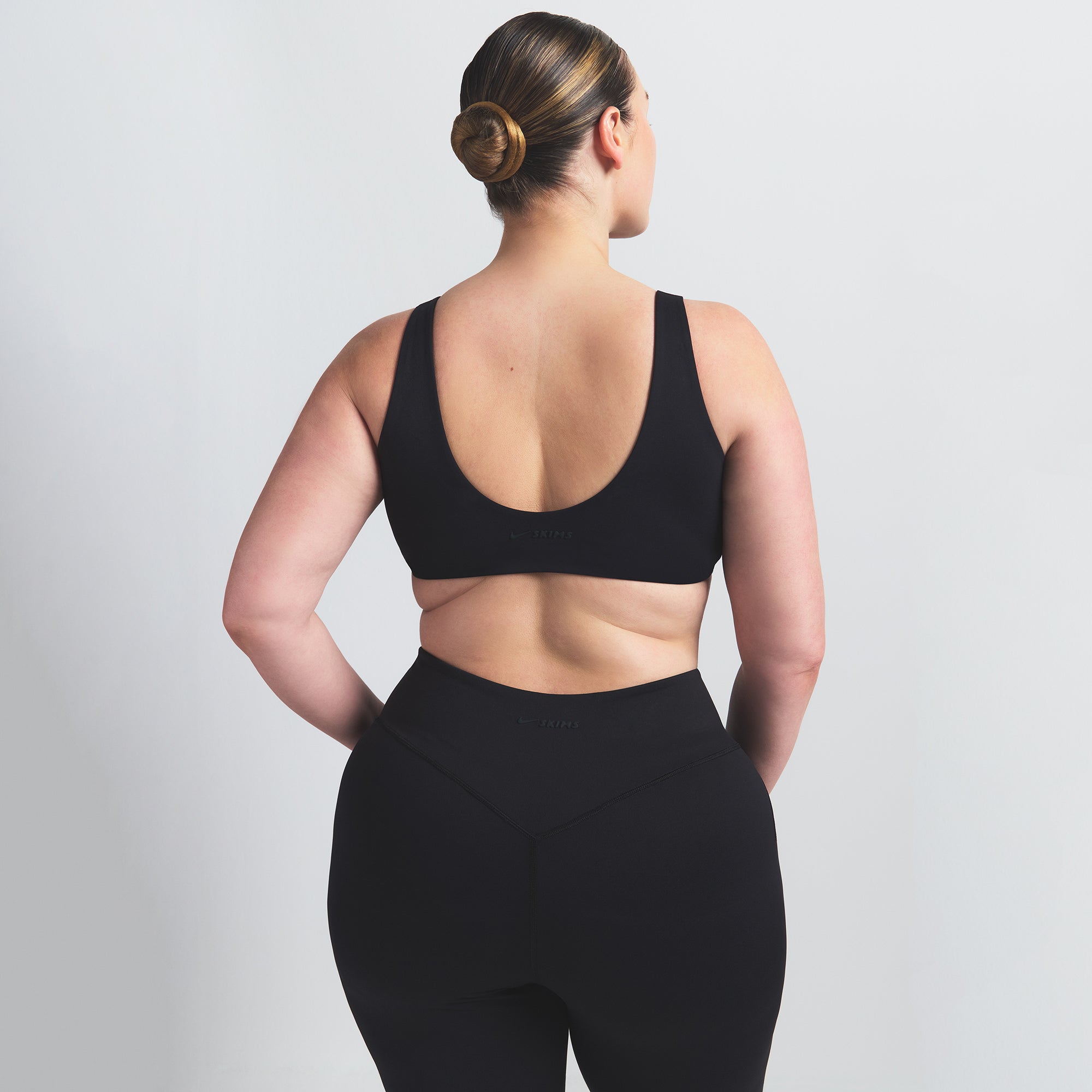 NikeSKIMS MATTE TWIST-FRONT BRA | OBSIDIAN ON A MODEL BACK VIEW @ | FOCUS: 0.0, 1.0, 0.9