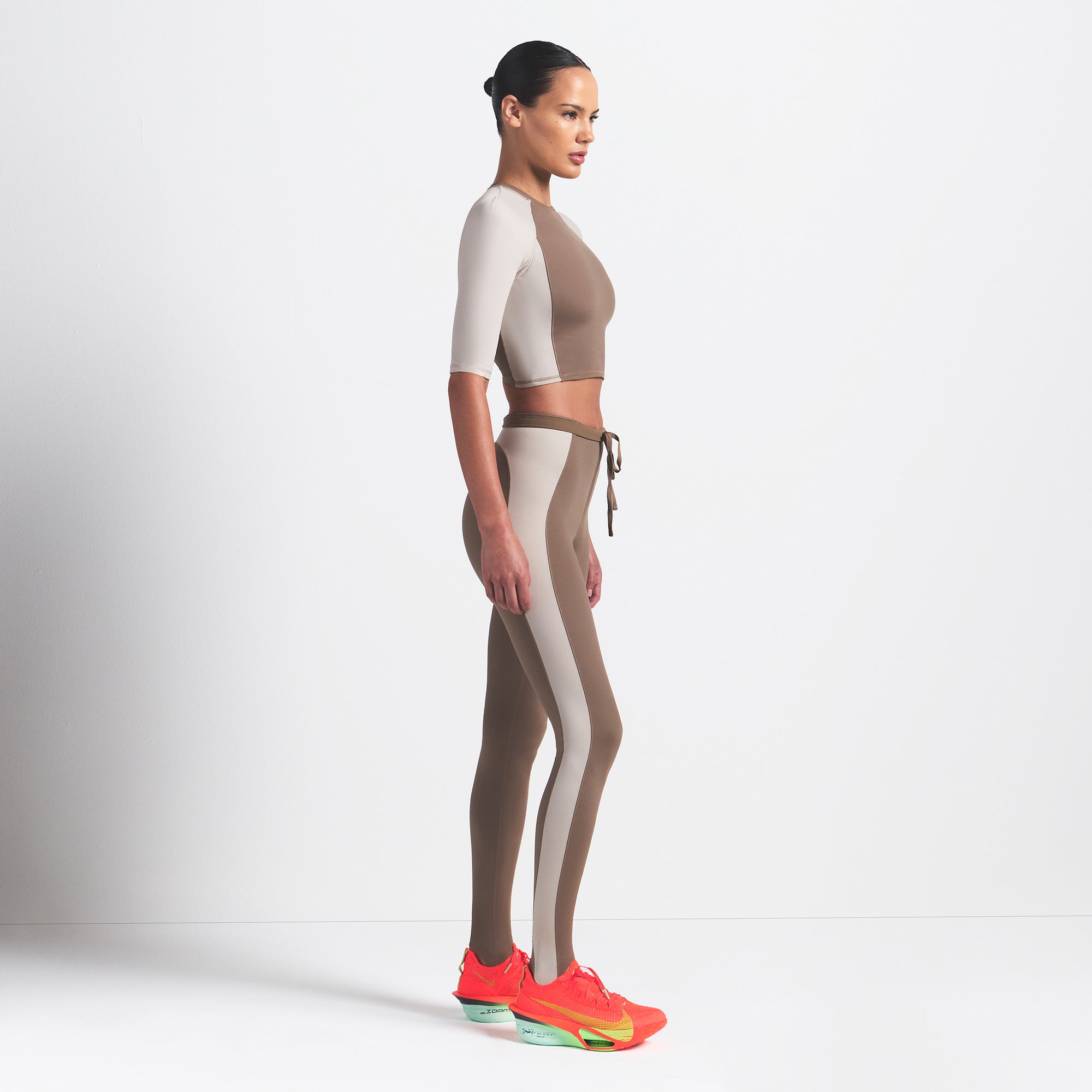 NikeSKIMS SHINE PADDED HALF SLEEVE CROP TOP | TRUFFLE AND STONE ON A MODEL SIDE VIEW @ | FOCUS: 0.0, 1.0, 0.9