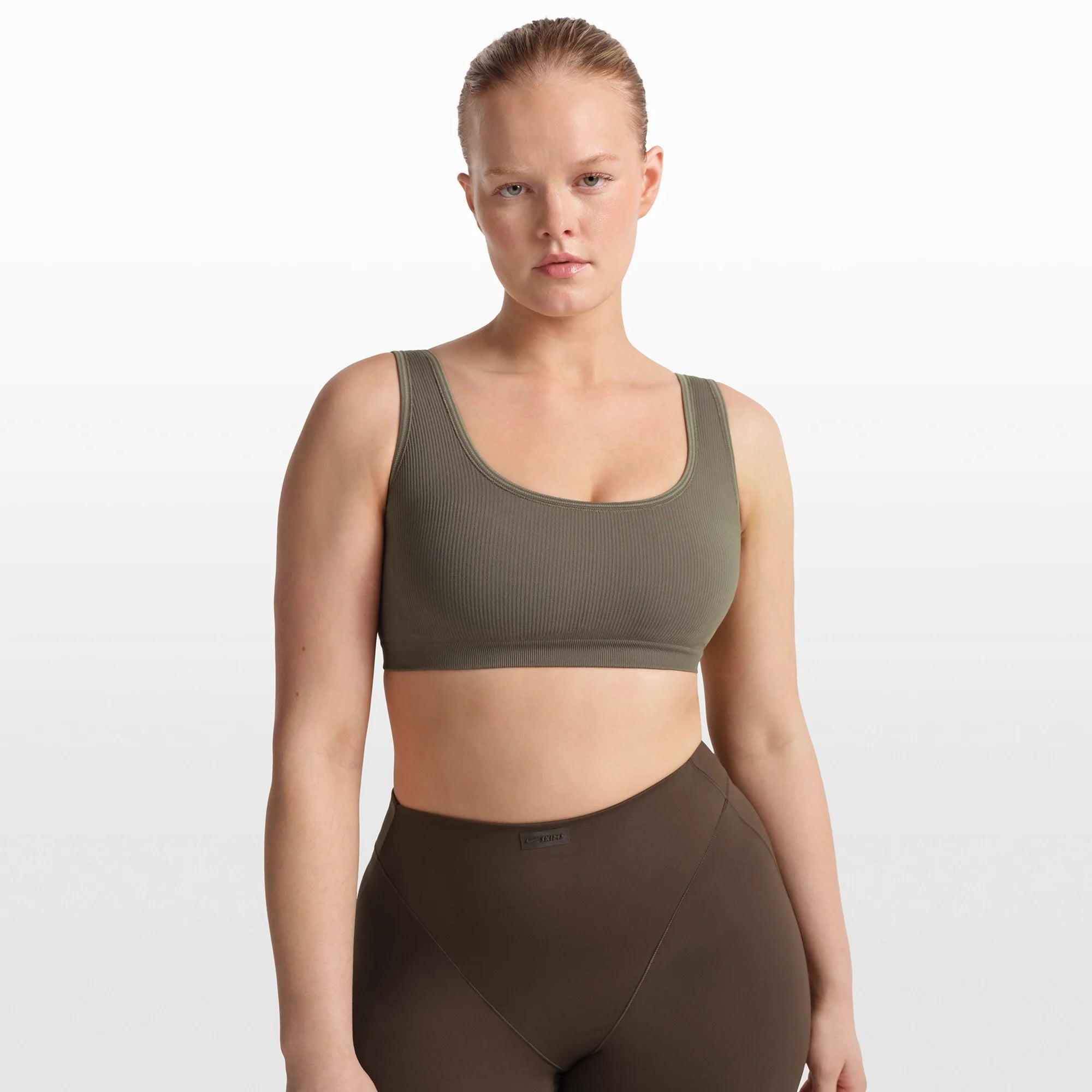 NikeSKIMS RIBBED SEAMLESS SCOOP BRA | DUSTY OAKMOSS/DUNE ON A MODEL FRONT VIEW @ | FOCUS: 0.0, 1.0, 0.9