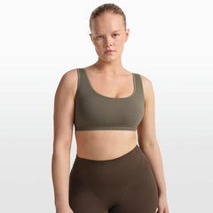 NikeSKIMS RIBBED SEAMLESS SCOOP BRA | DUSTY OAKMOSS/DUNE ON A MODEL FRONT VIEW @ | FOCUS: 0.0, 1.0, 0.9