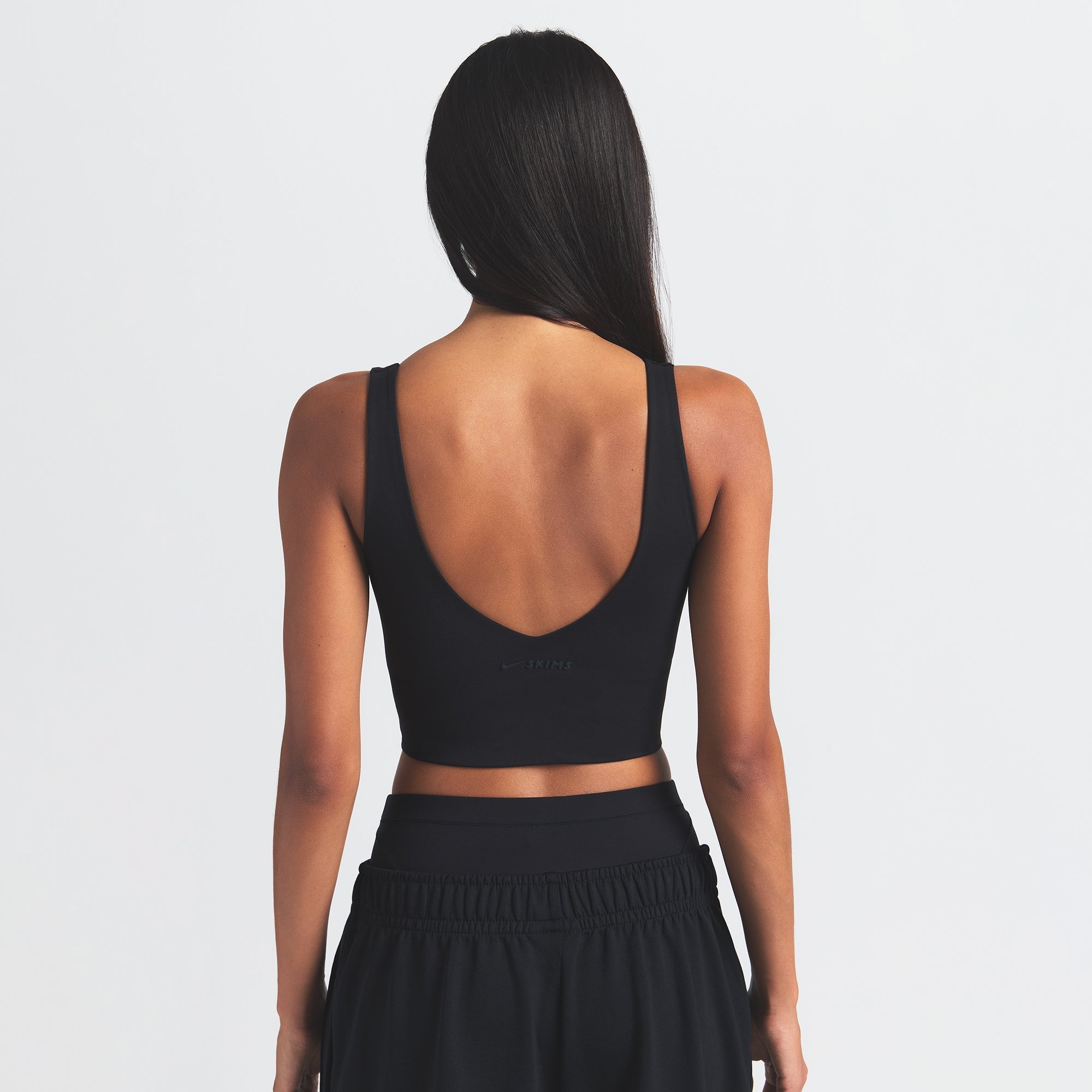 NikeSKIMS MATTE V-NECK BRA TOP | OBSIDIAN ON A MODEL BACK VIEW @ | FOCUS: 0.0, 1.0, 0.9