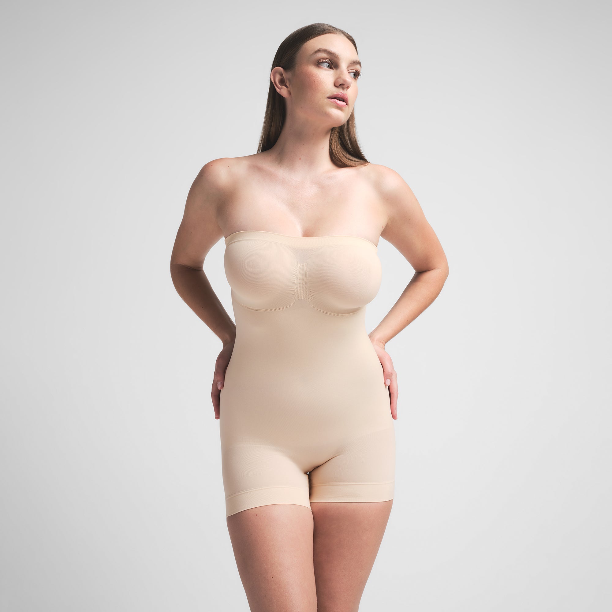 SEAMLESS SCULPT STRAPLESS SHORTIE BODYSUIT | SAND ON A MODEL FRONT VIEW