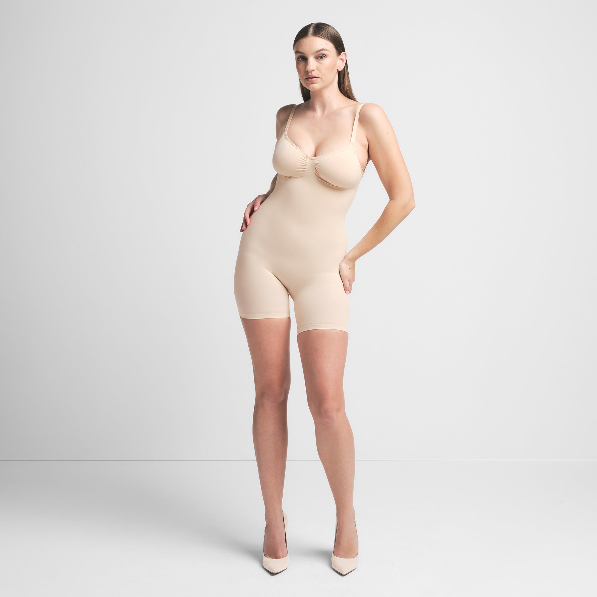 SEAMLESS SCULPT LOW BACK MID THIGH BODYSUIT | SAND ON A MODEL FRONT VIEW