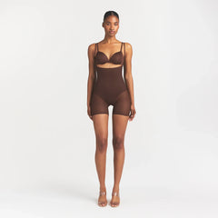 SKIMS BODY CORE SCULPT BACK SMOOTHING OPEN BUST MID THIGH BODYSUIT | COCOA ON A MODEL FRONT VIEW @
