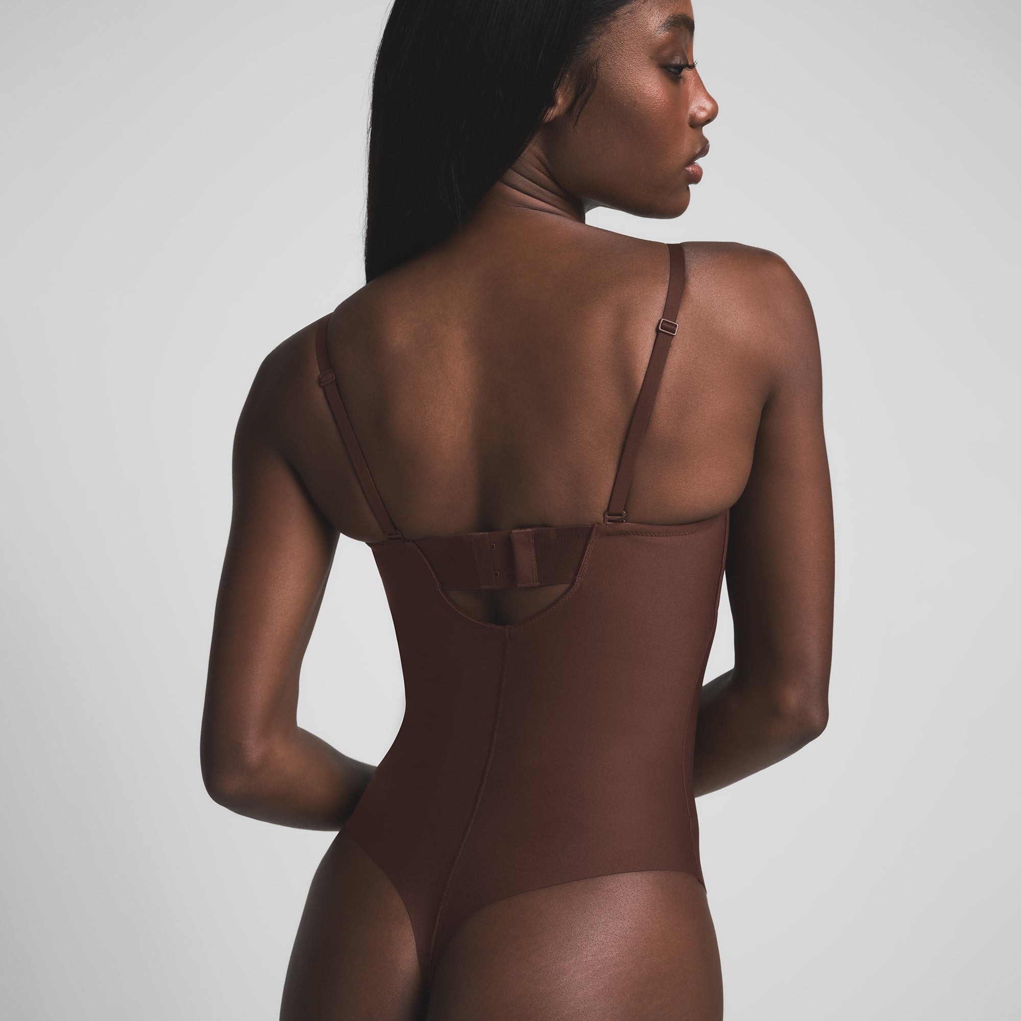 SKIMS BODY UNDERWIRE THONG BODYSUIT | COCOA ON A MODEL BACK VIEW | FOCUS: 0.9, 0.1, 0.7