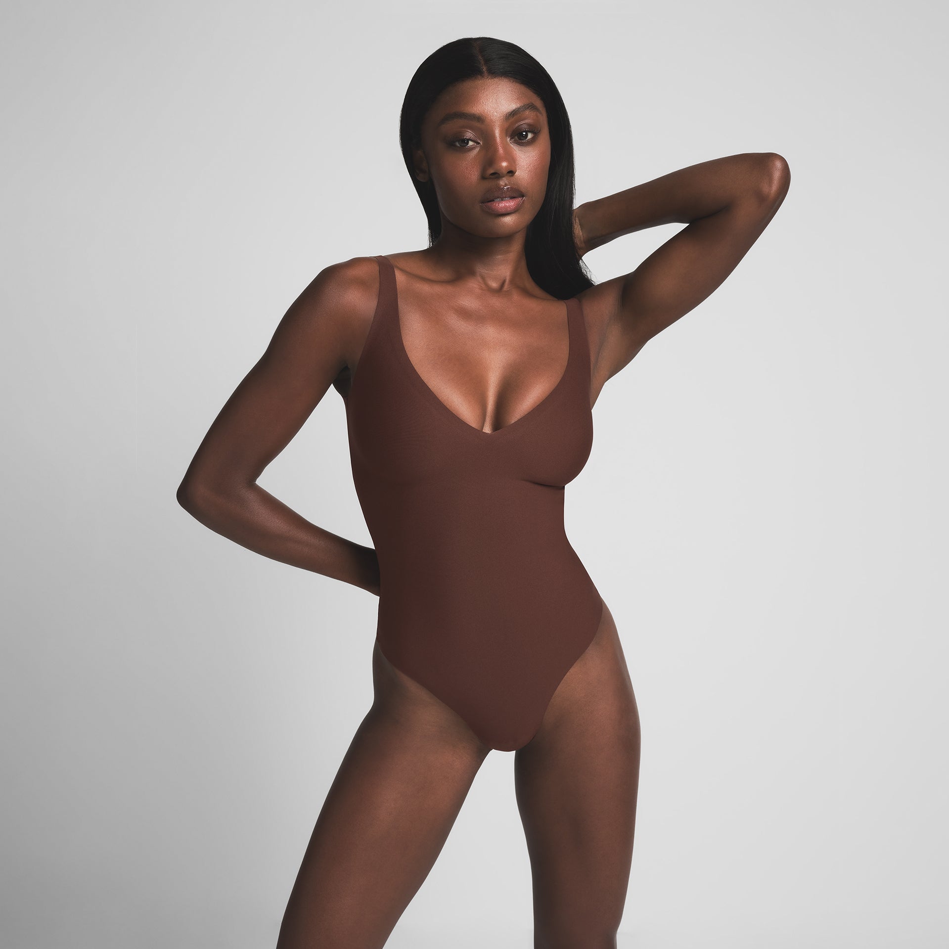 SKIMS BODY UNLINED PLUNGE THONG BODYSUIT | COCOA ON A MODEL FRONT VIEW