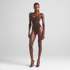 SHEER SEAMLESS THONG BODYSUIT | COCOA ON A MODEL FRONT VIEW