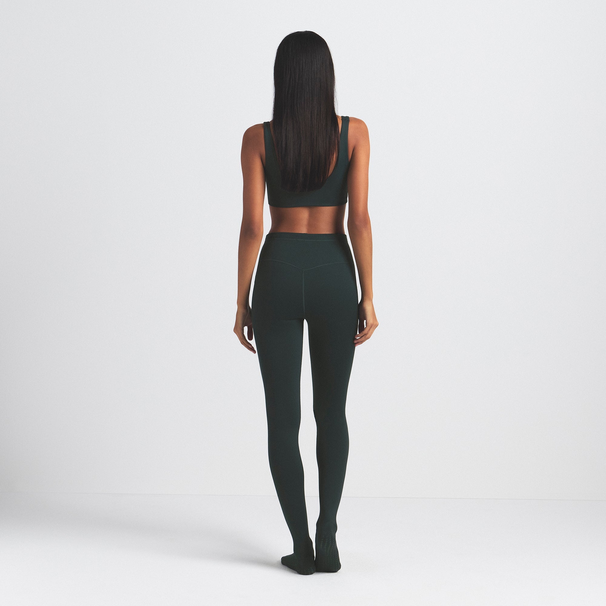 NikeSKIMS MATTE FOOTSIE GRIP LEGGING | DARK TEAL ON A MODEL SIDE VIEW @ | FOCUS: 0.0, 1.0, 0.9