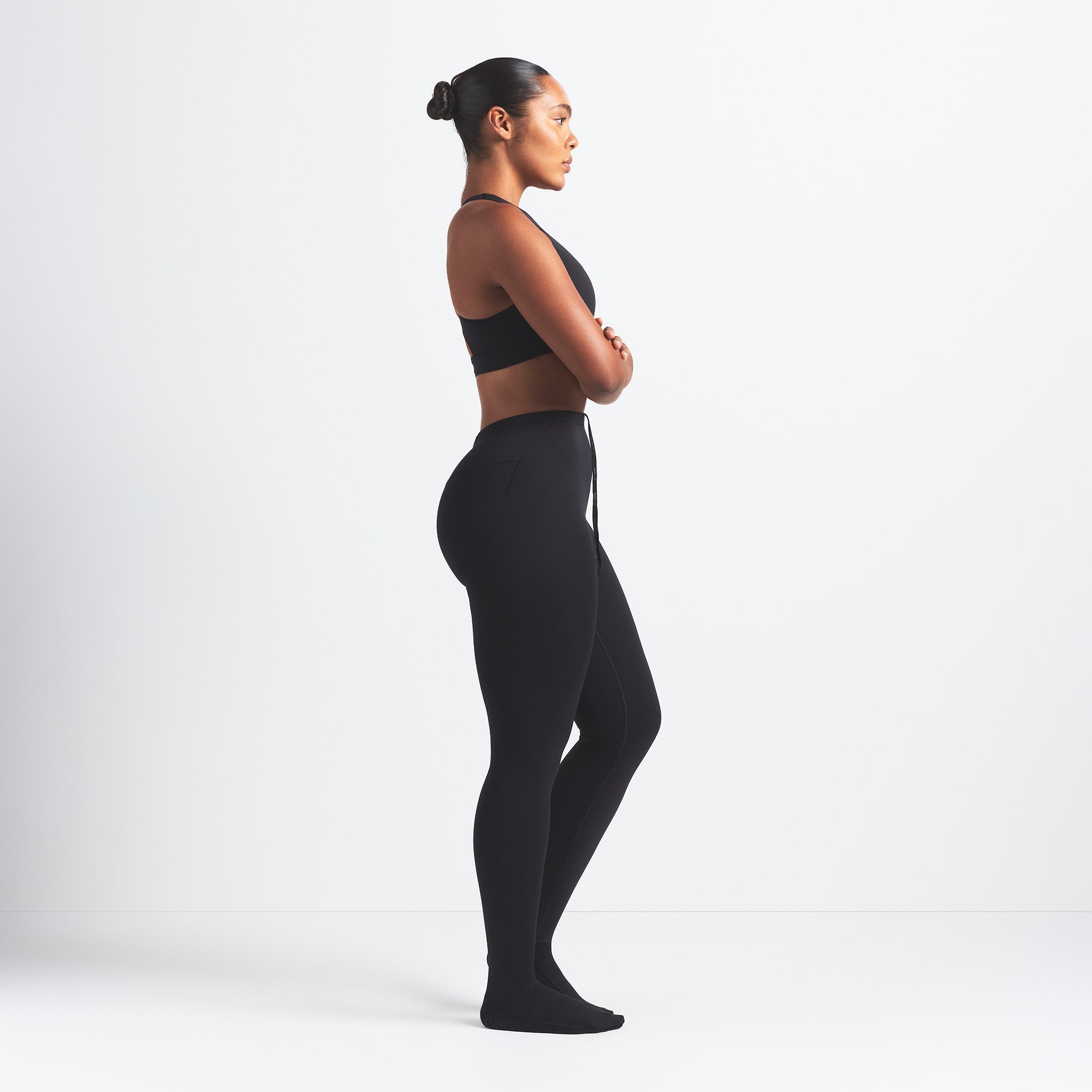 NikeSKIMS MATTE FOOTSIE GRIP LEGGING | OBSIDIAN ON A MODEL SIDE VIEW @ | FOCUS: 0.0, 1.0, 0.9