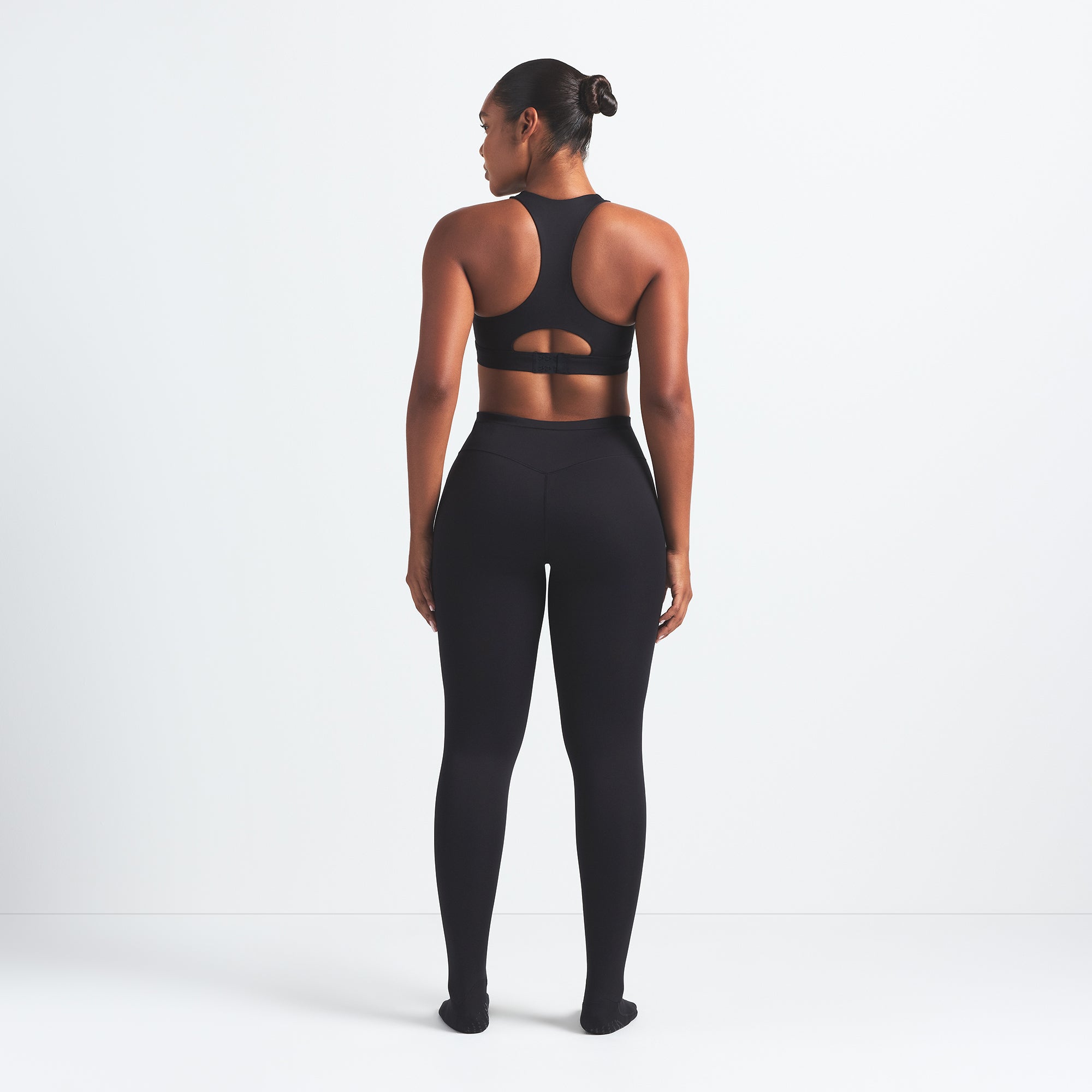 NikeSKIMS MATTE FOOTSIE GRIP LEGGING | OBSIDIAN ON A MODEL BACK VIEW @ | FOCUS: 0.0, 1.0, 0.9