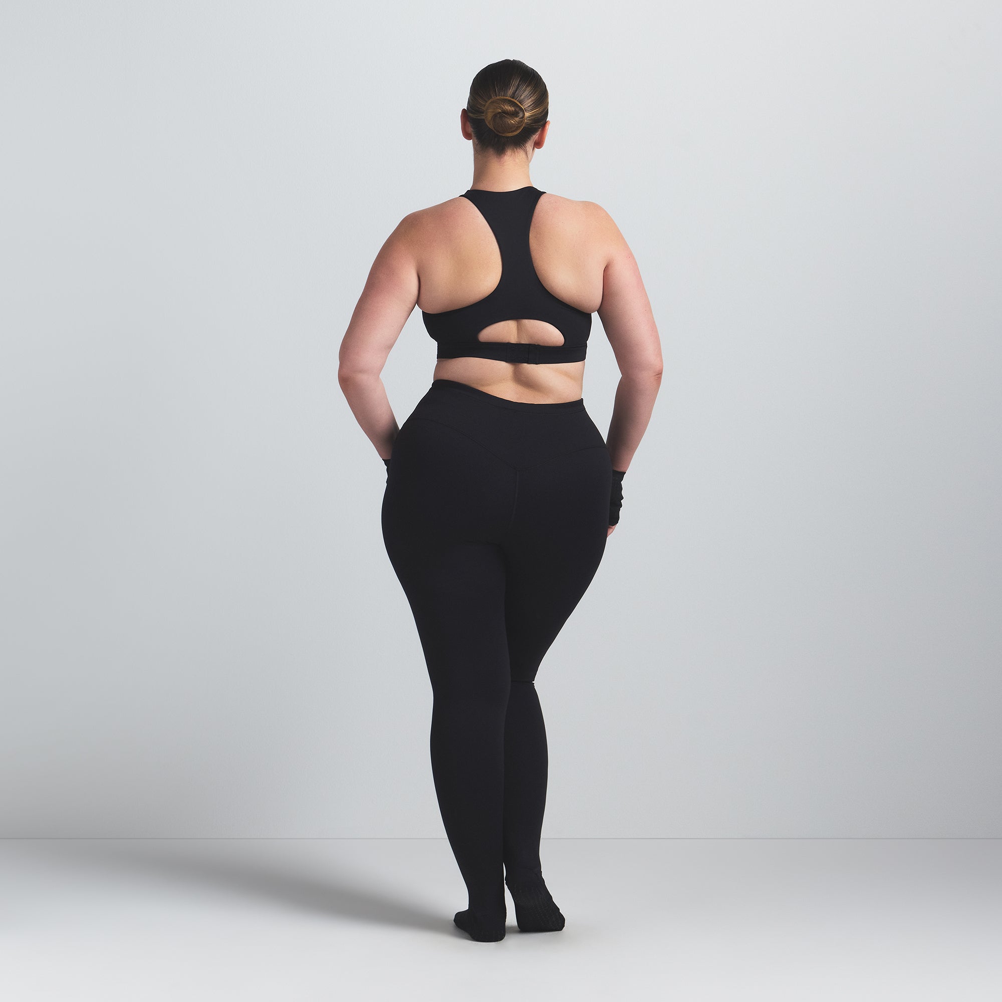 NikeSKIMS MATTE FOOTSIE GRIP LEGGING | OBSIDIAN ON A MODEL BACK VIEW @ | FOCUS: 0.0, 1.0, 0.9