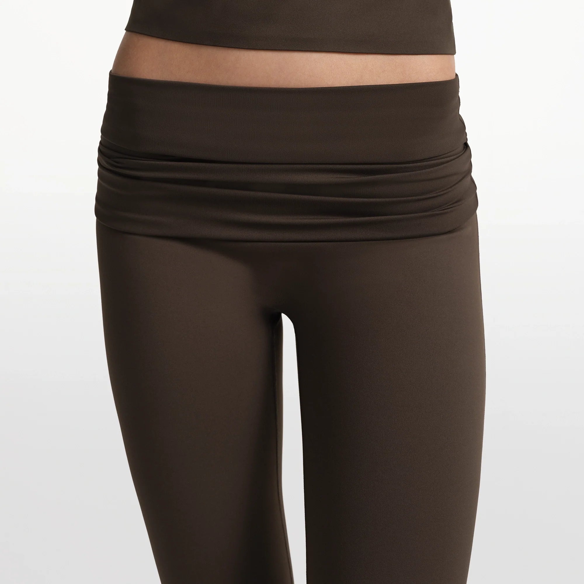 NikeSKIMS MATTE FOLDOVER SLIM FLARE LEGGING | DARK SEPIA ON A MODEL FRONT VIEW @ | FOCUS: 0.0, 1.0, 0.9