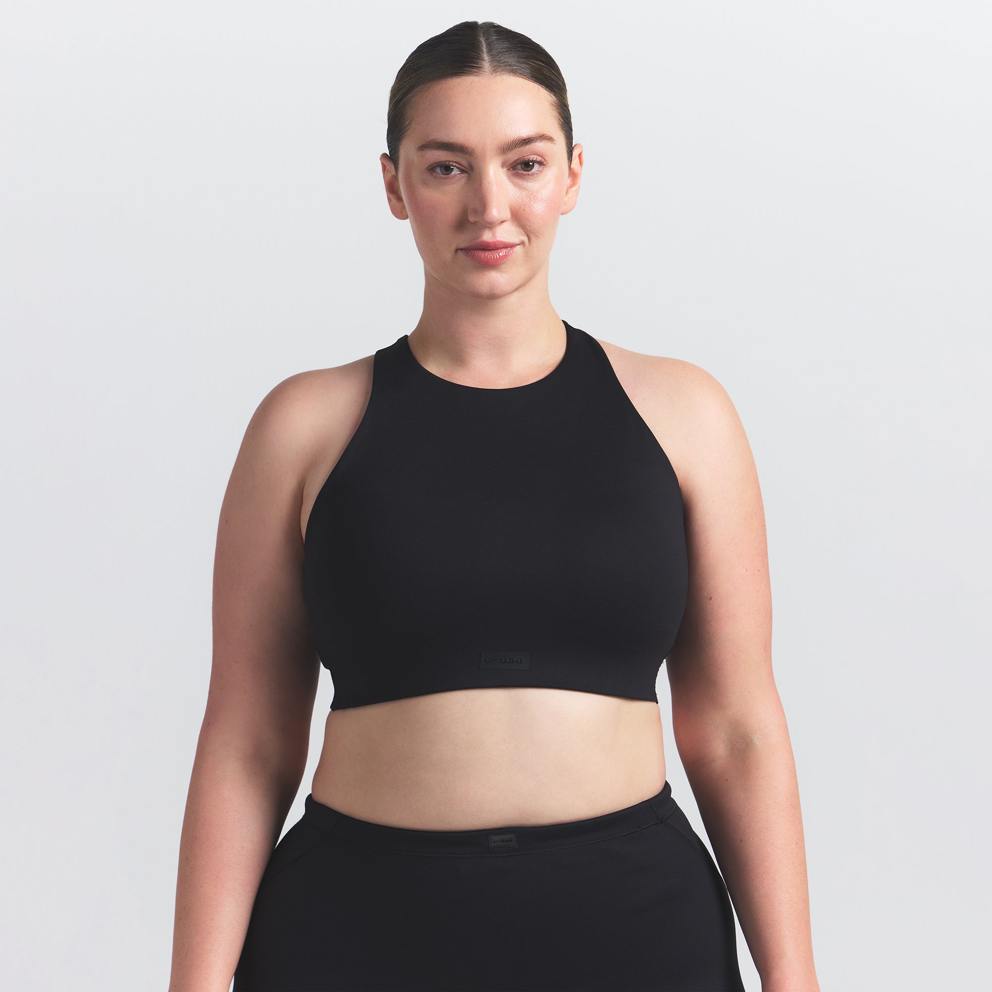 NikeSKIMS MATTE HIGH NECK BRA | OBSIDIAN ON A MODEL FRONT VIEW @ | FOCUS: 0.0, 1.0, 0.9