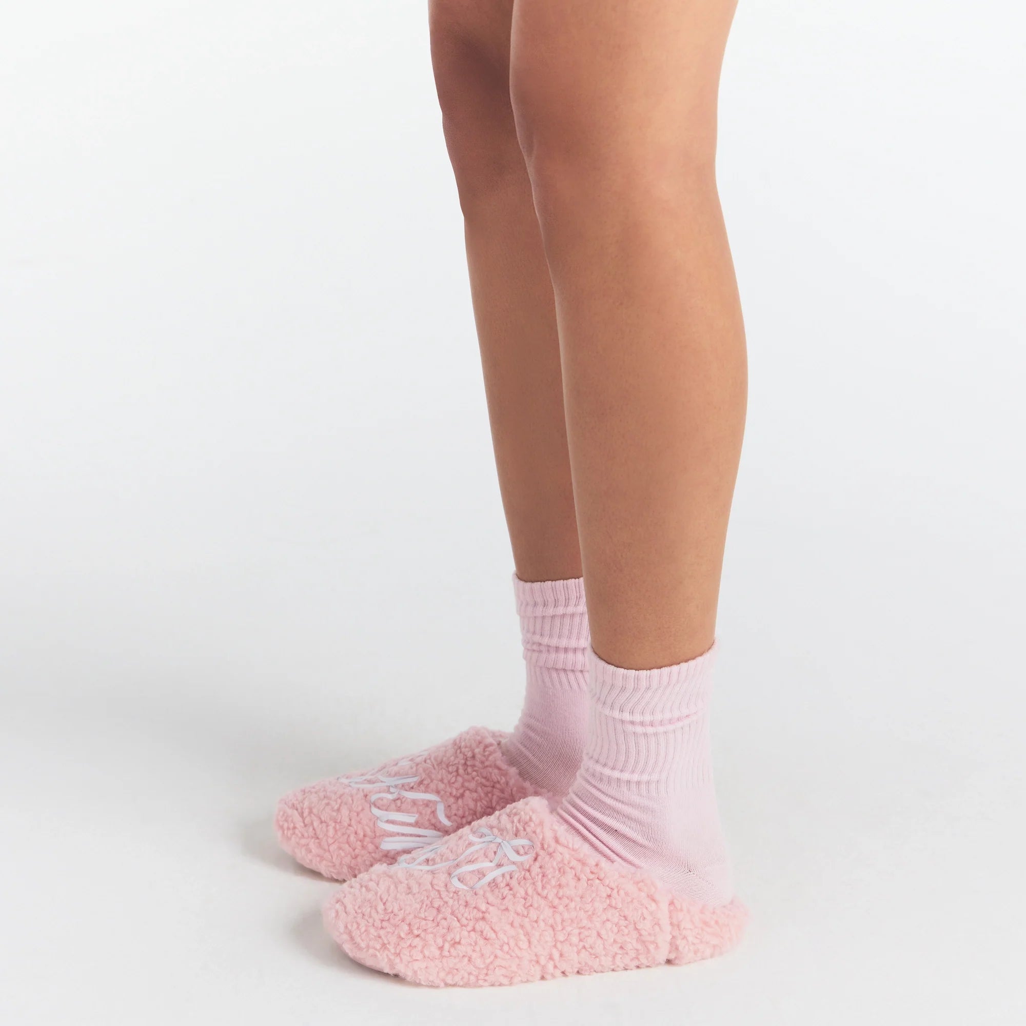 SKIMS ACCESSORIES SHERPA SLIPPER | PEONY SKIMS BOW ON A MODEL SIDE VIEW @ | FOCUS: 0.0, 1.0, 0.9