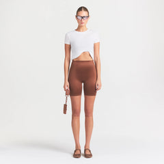 NikeSKIMS SATIN SHINE BONDED WAIST 7" BIKER SHORT | CAROB BROWN ON A MODEL FRONT VIEW @ | FOCUS: 0.0, 1.0, 0.9