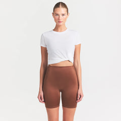 NikeSKIMS SATIN SHINE BONDED WAIST 7" BIKER SHORT | CAROB BROWN ON A MODEL SIDE VIEW @ | FOCUS: 0.0, 1.0, 0.9