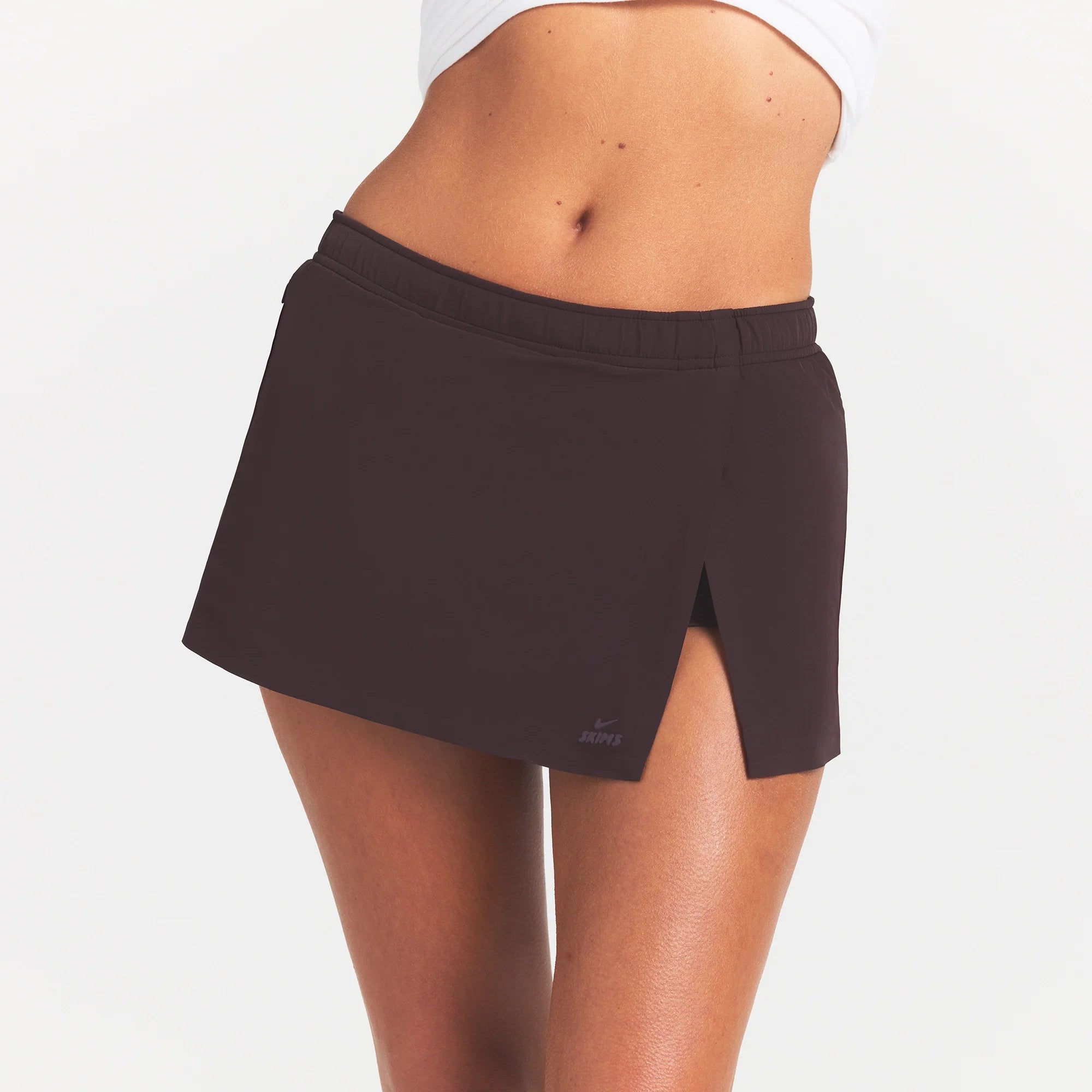 NikeSKIMS STRETCH NYLON SKORT | DARK ROAST ON A MODEL SIDE VIEW @ | FOCUS: 0.0, 1.0, 0.9