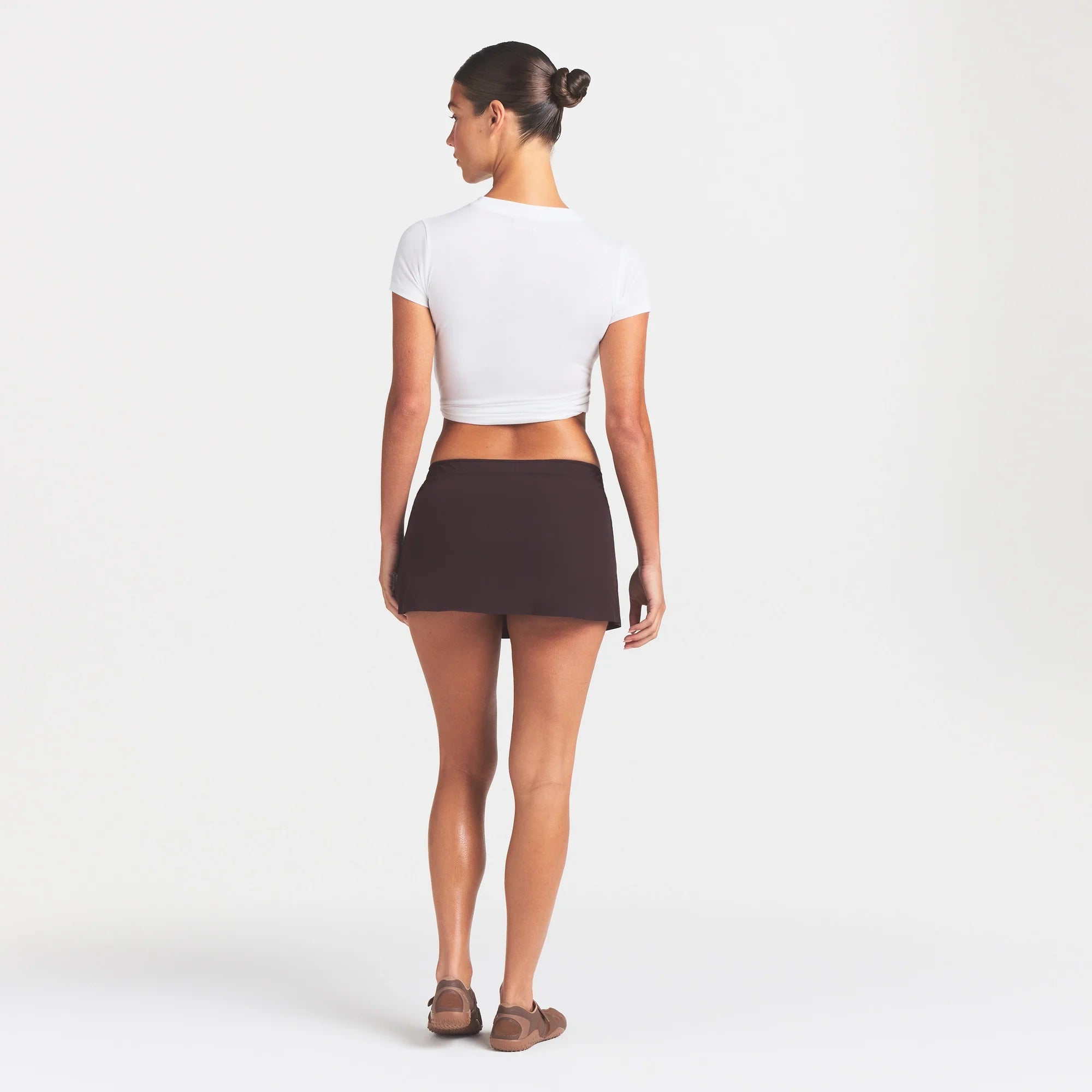 NikeSKIMS STRETCH NYLON SKORT | DARK ROAST ON A MODEL FRONT VIEW @ | FOCUS: 0.0, 1.0, 0.9