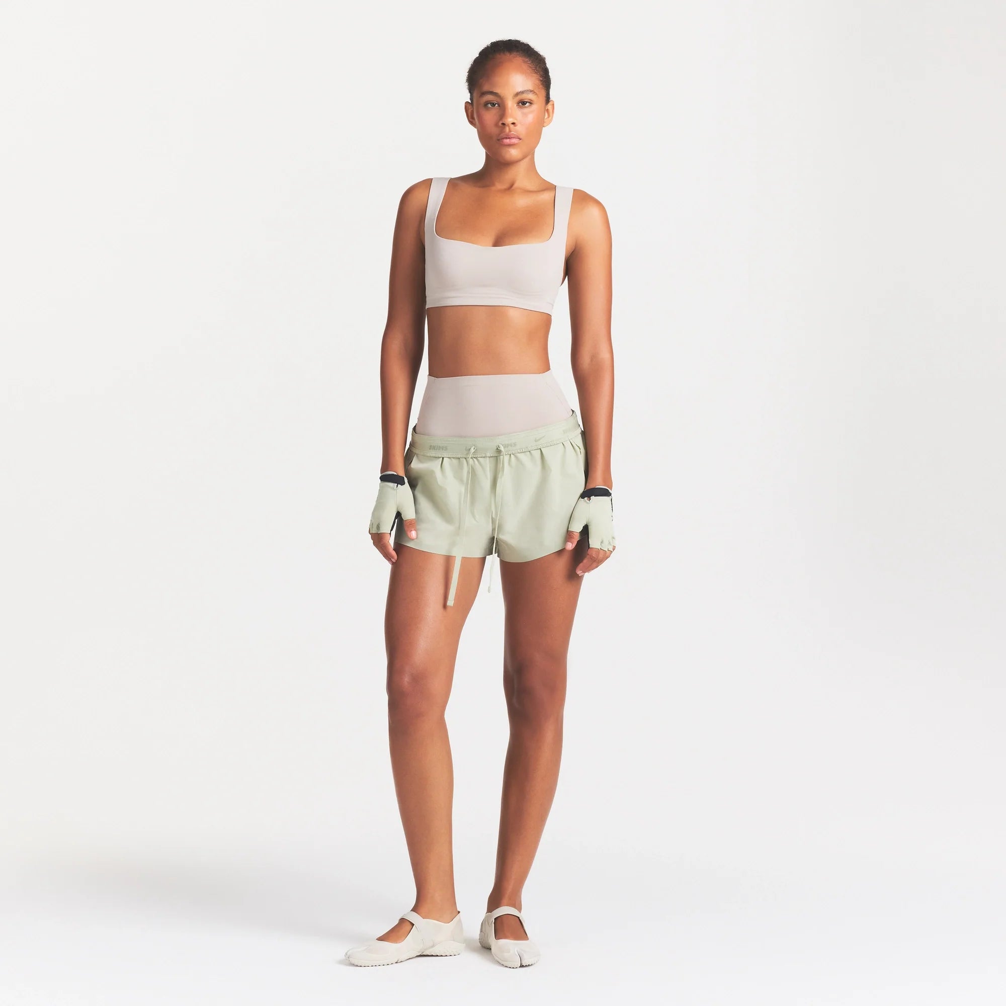 NikeSKIMS ACCESSORIES TRAINING GLOVES | TALC ON A MODEL FRONT VIEW @ | FOCUS: 0.0, 1.0, 0.9