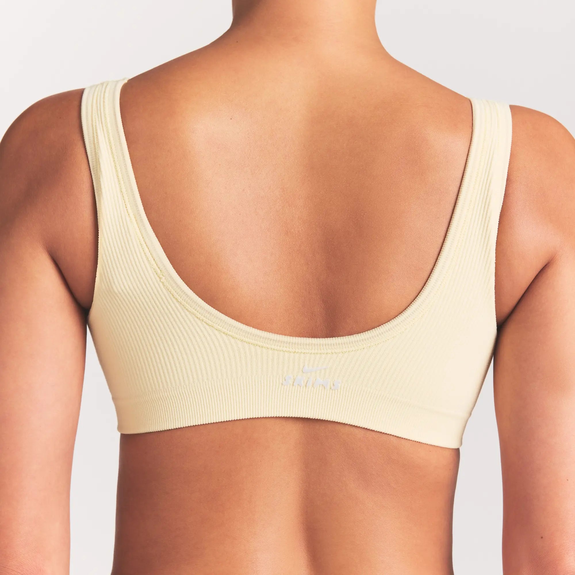 NikeSKIMS RIBBED SEAMLESS MICRO SCOOP BRA | LEMON DROP ON A MODEL SIDE VIEW @ | FOCUS: 0.0, 1.0, 0.9