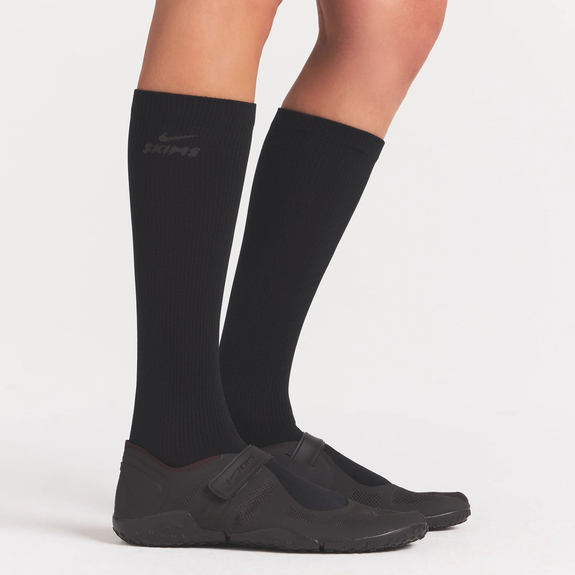 NikeSKIMS ACCESSORIES RIFT KNEE HIGH SOCK | OBSIDIAN/BOULDER ON A MODEL SIDE VIEW @ | FOCUS: 0.0, 1.0, 0.9
