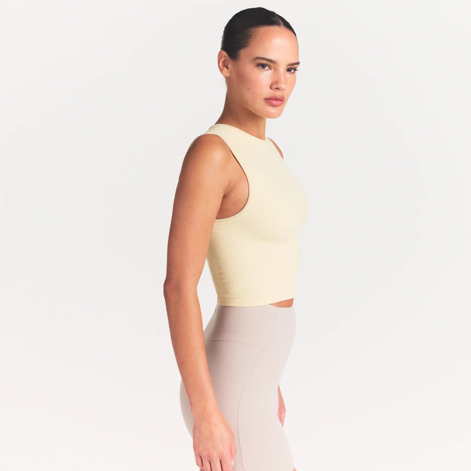 NikeSKIMS RIBBED SEAMLESS MUSCLE TANK | LEMON DROP ON A MODEL SIDE VIEW @ | FOCUS: 0.0, 1.0, 0.9
