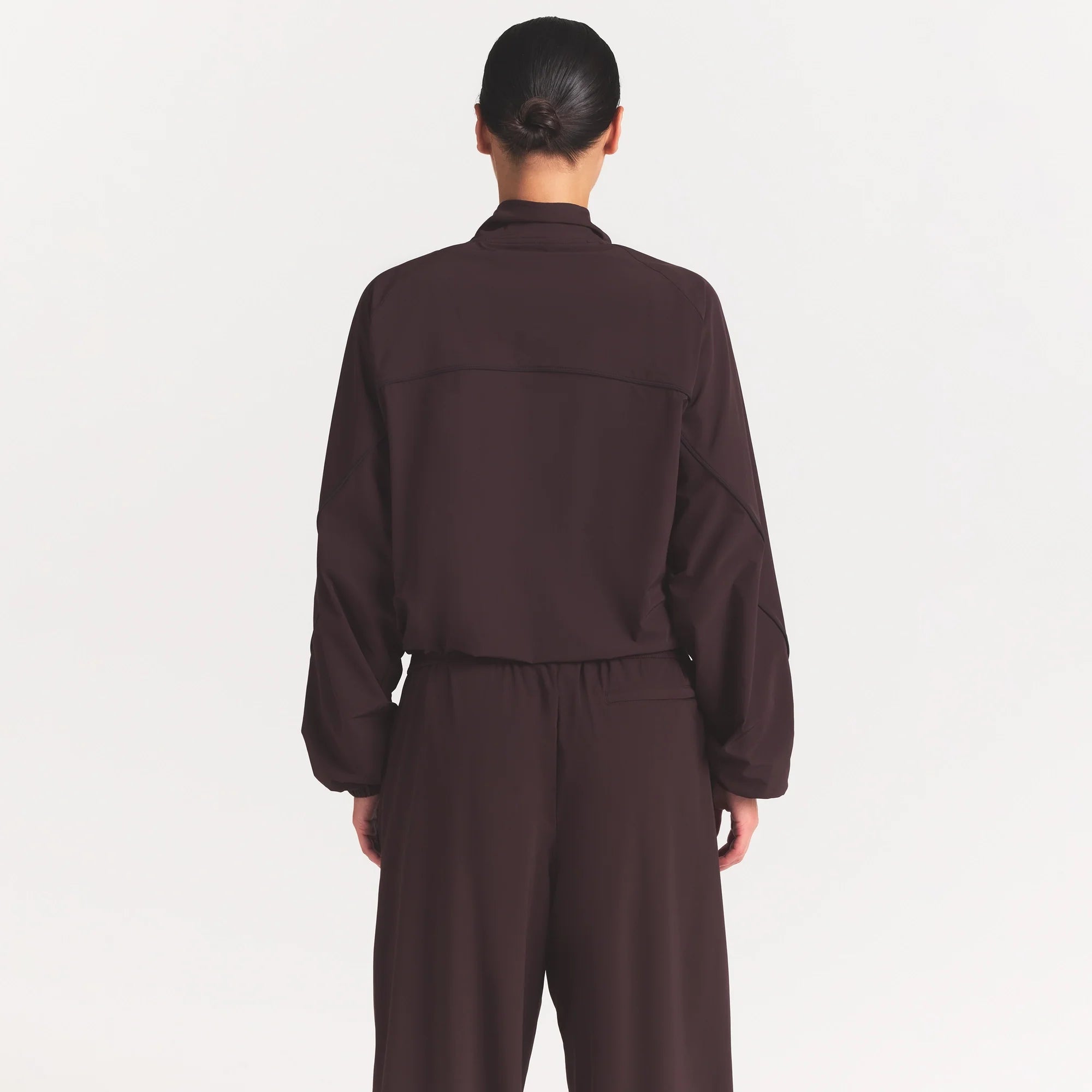 NikeSKIMS STRETCH NYLON OVERSIZED TRACK JACKET | DARK ROAST ON A MODEL SIDE VIEW @ | FOCUS: 0.0, 1.0, 0.9
