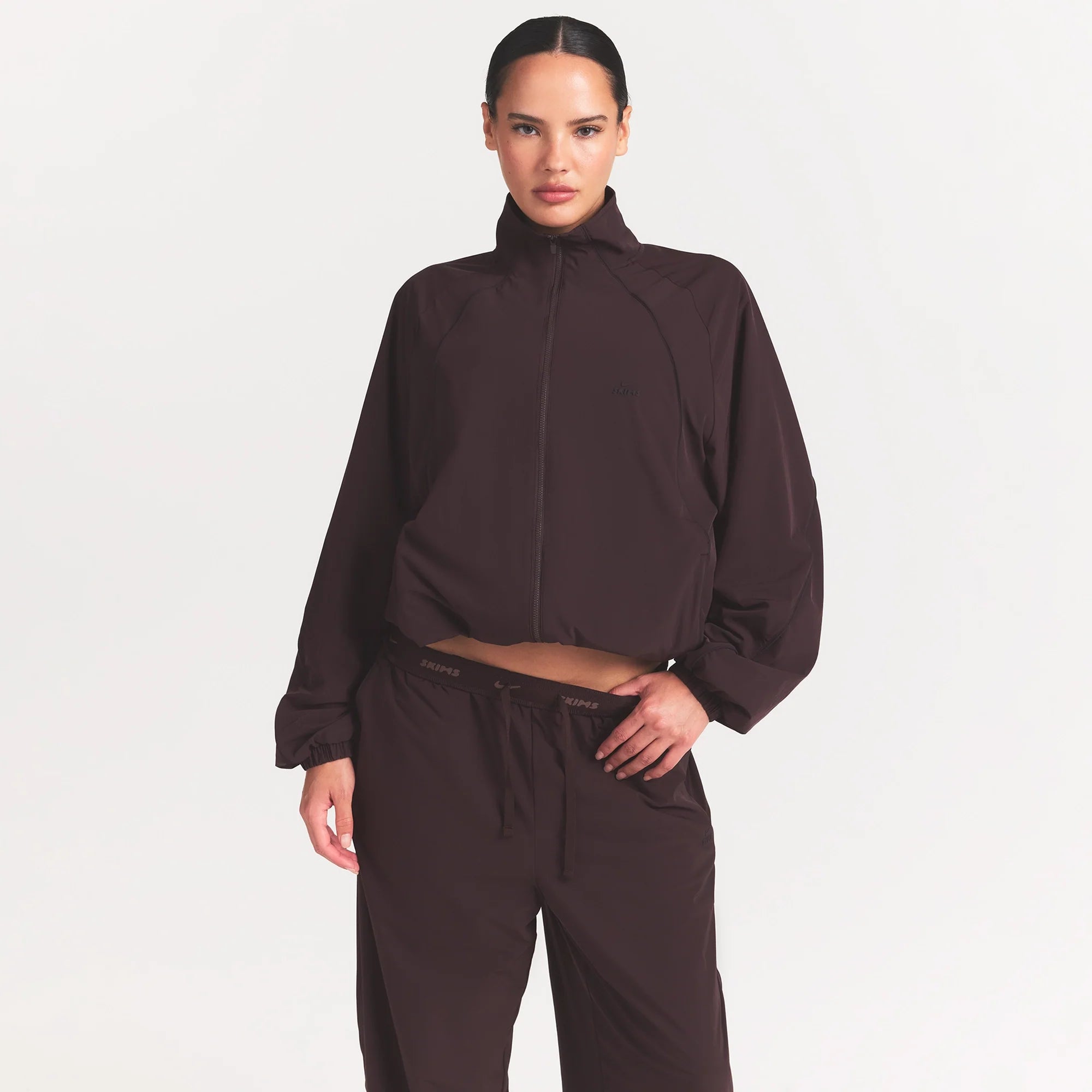 NikeSKIMS STRETCH NYLON OVERSIZED TRACK JACKET | DARK ROAST ON A MODEL SIDE VIEW @ | FOCUS: 0.0, 1.0, 0.9