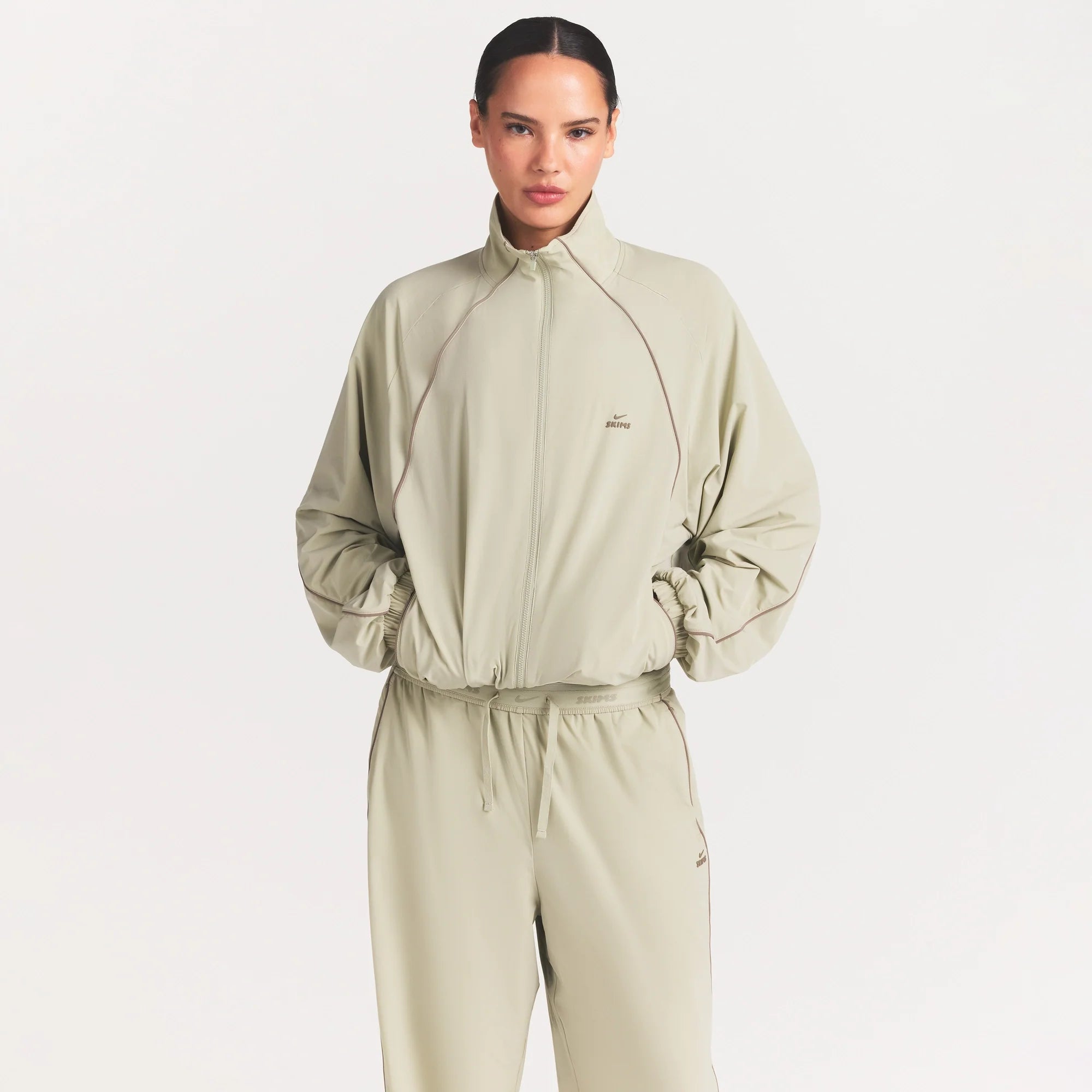 NikeSKIMS STRETCH NYLON OVERSIZED TRACK JACKET | TALC ON A MODEL SIDE VIEW @ | FOCUS: 0.0, 1.0, 0.9