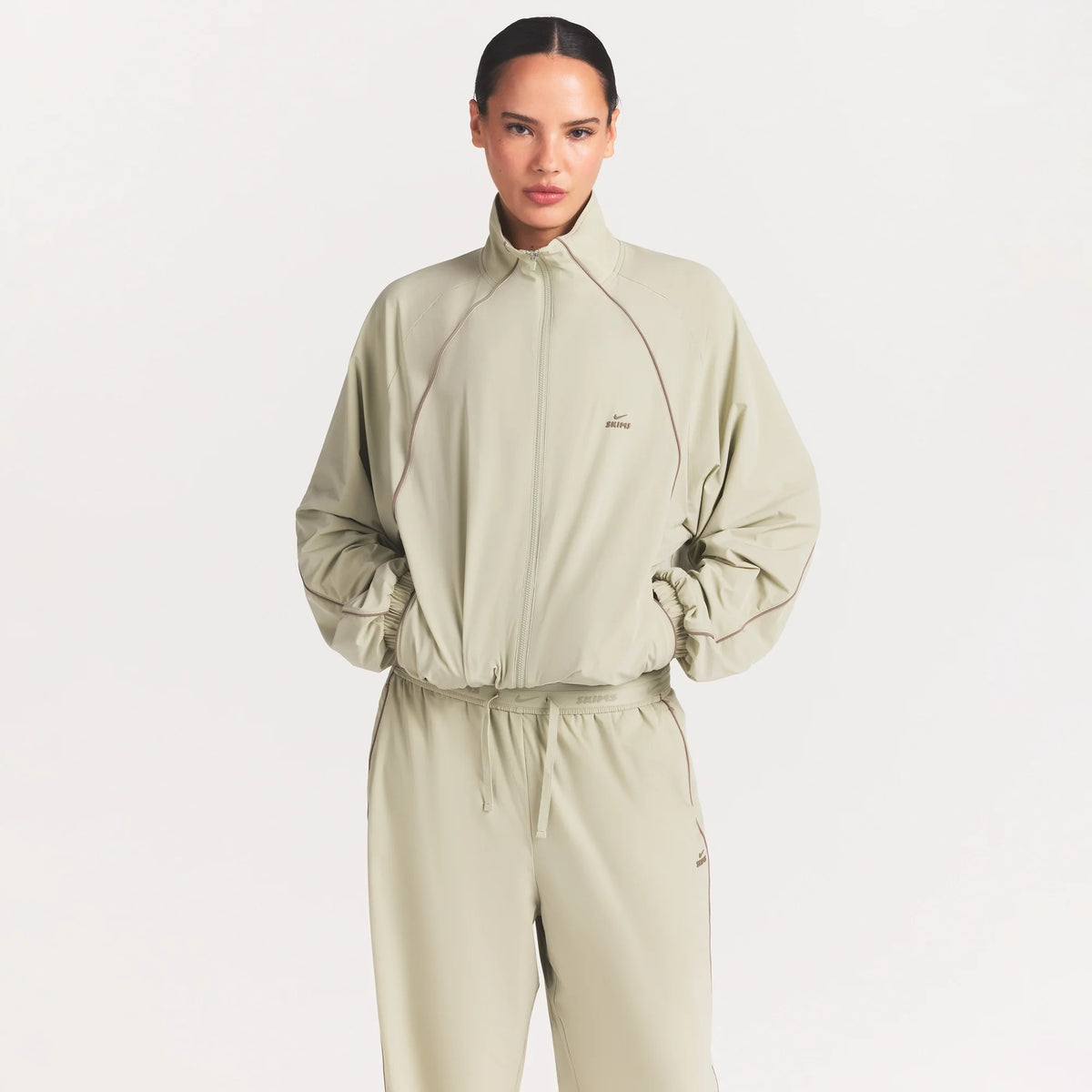 NikeSKIMS STRETCH NYLON OVERSIZED TRACK JACKET | TALC ON A MODEL SIDE VIEW @ | FOCUS: 0.0, 1.0, 0.9