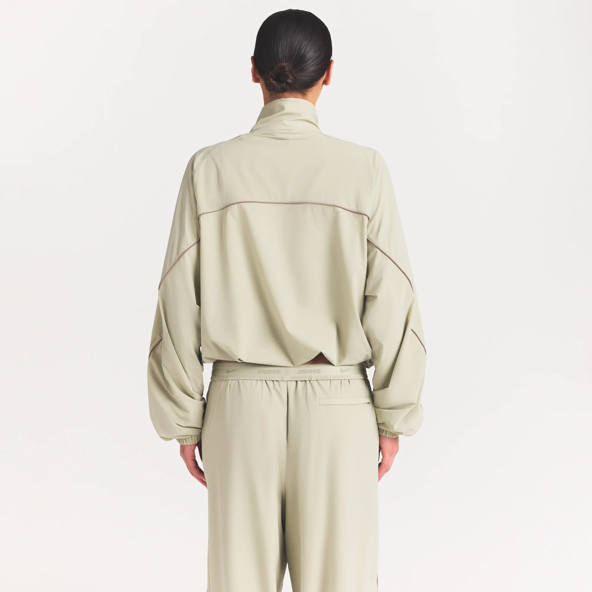 NikeSKIMS STRETCH NYLON OVERSIZED TRACK JACKET | TALC ON A MODEL SIDE VIEW @ | FOCUS: 0.0, 1.0, 0.9