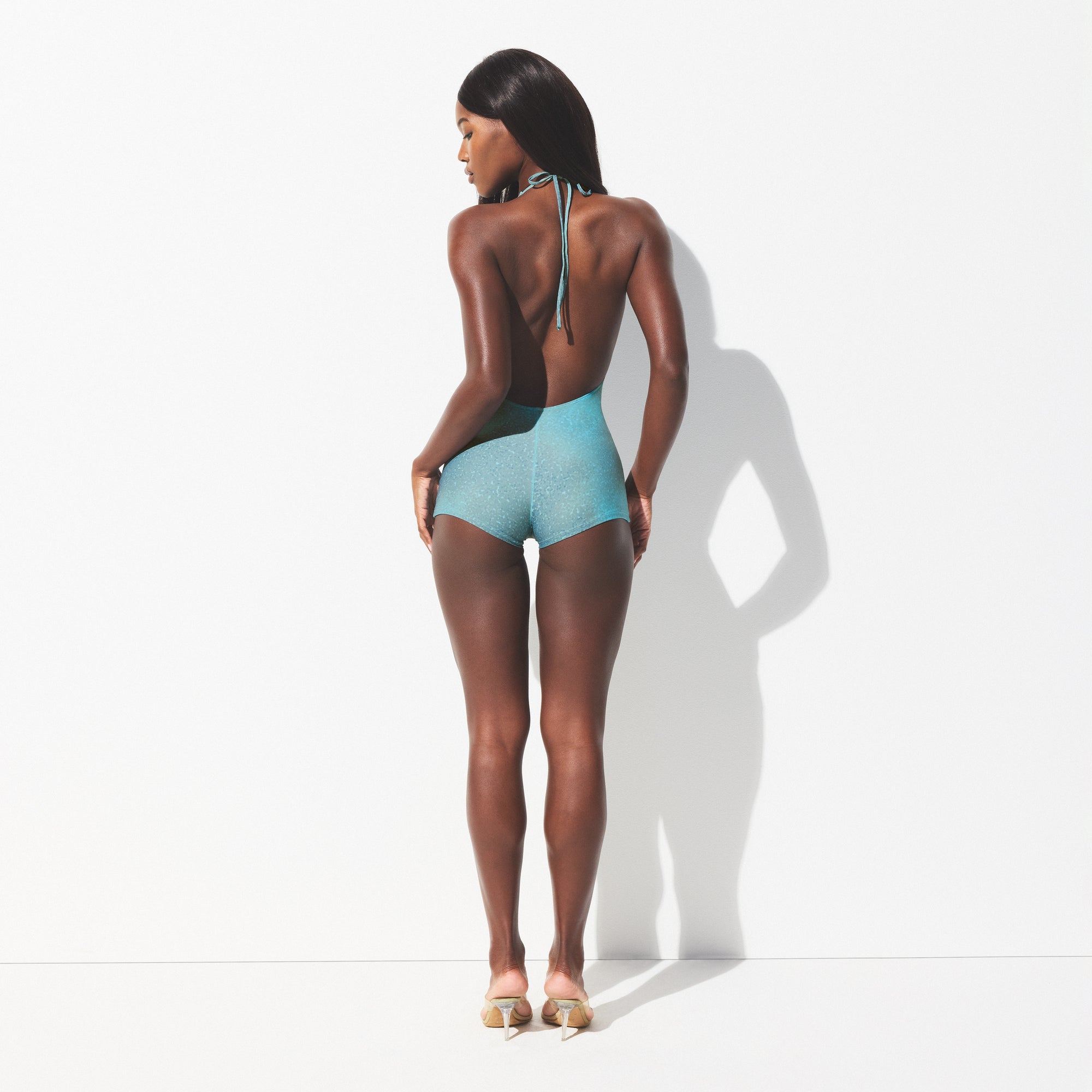 SIGNATURE SWIM PLUNGE SHORTIE ONE PIECE | CYAN FK OMBRE PRINT ON A MODEL SIDE VIEW 