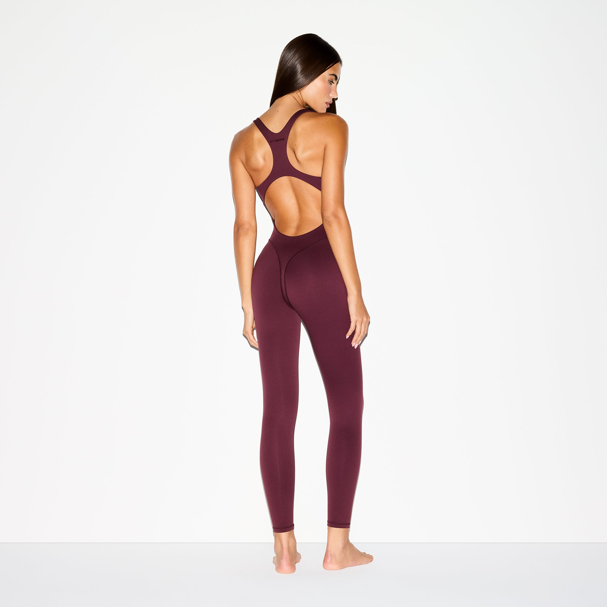 NikeSKIMS MATTE RACER LONG ONESIE | CURRANT ON A MODEL BACK VIEW @ | FOCUS: 0.0, 1.0, 0.9