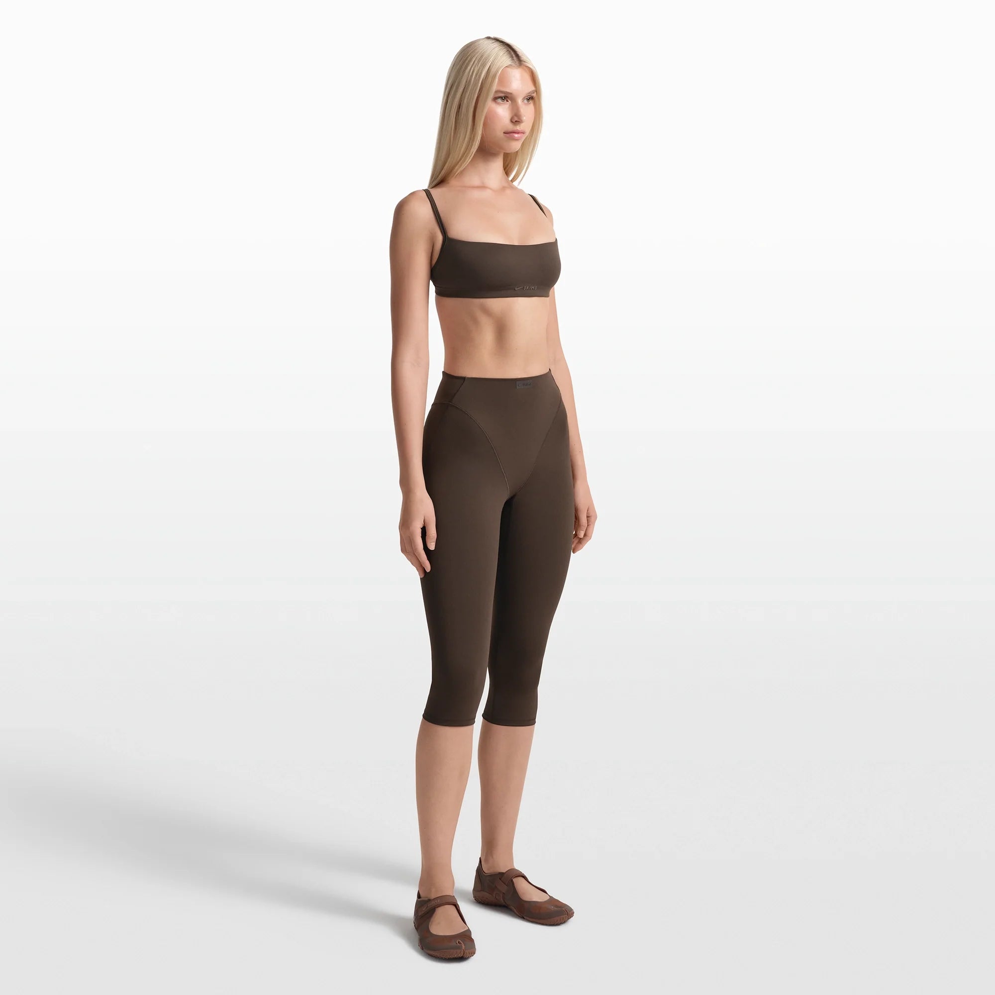NikeSKIMS MATTE 17" V-LINE CROP LEGGING | DARK SEPIA ON A MODEL FRONT VIEW @ | FOCUS: 0.0, 1.0, 0.9