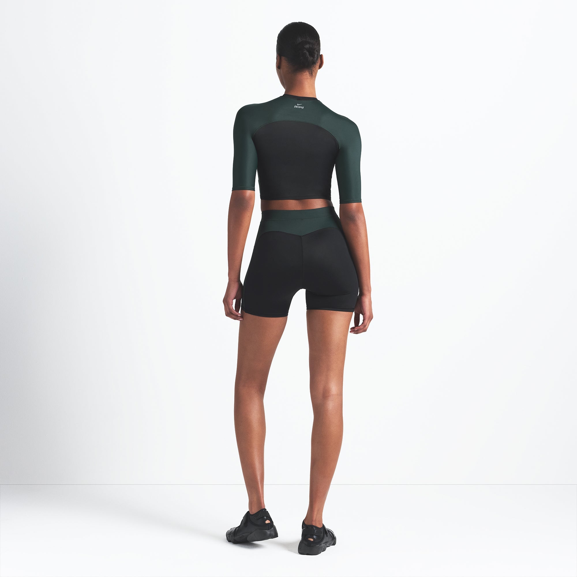 NikeSKIMS SHINE 5" BIKER SHORT | OBSIDIAN AND DARK TEAL ON A MODEL BACK VIEW @ | FOCUS: 0.0, 1.0, 0.9