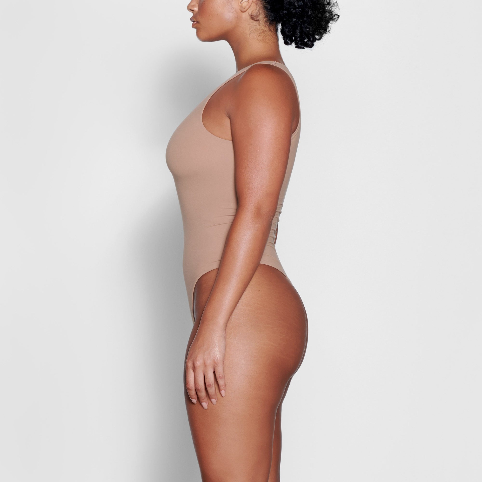 A MODEL STANDS SIDEWAYS SHOWING THE PROFILE OF THE FITS EVERYBODY HIGH NECK BODYSUIT | SIENNA