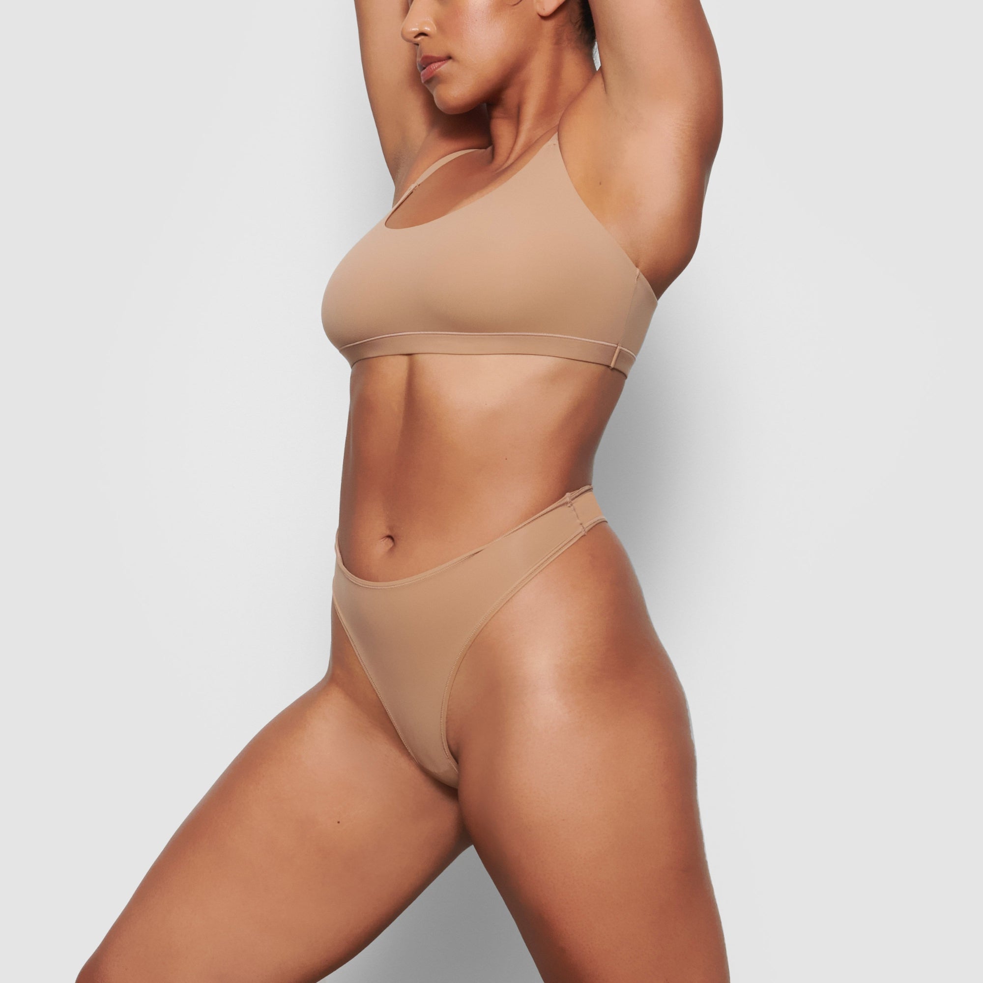 A MODEL STANDS SIDEWAYS SHOWING THE PROFILE OF THE FITS EVERYBODY SCOOP NECK BRA | SIENNA
