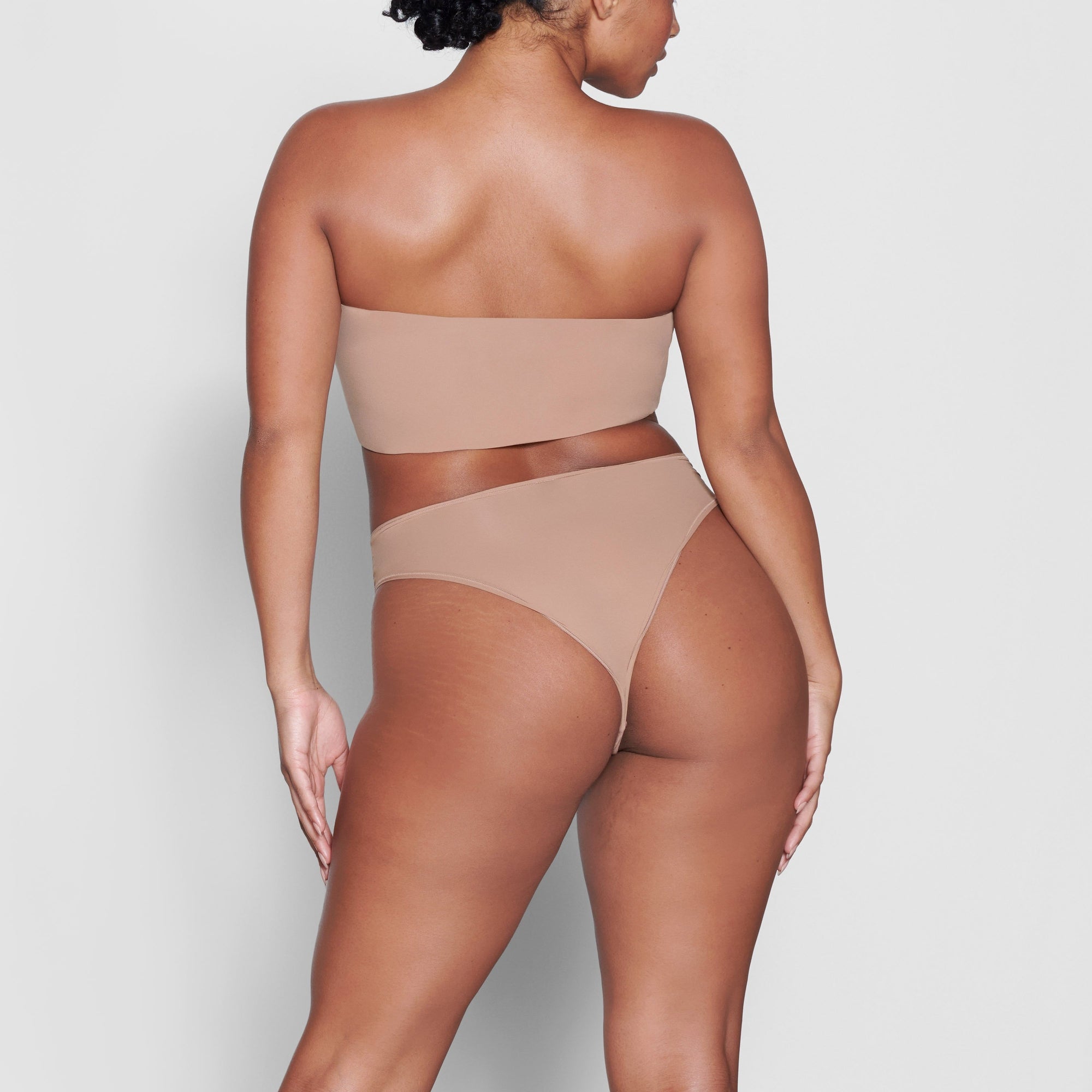 A MODEL STANDS WITH HER BACK TO THE CAMERA SHOWING THE FITS EVERYBODY BANDEAU BRA | SIENNA